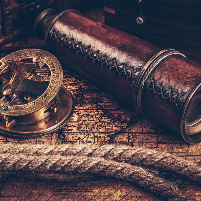 Travel geography navigation concept still life background - old vintage retro compass with sundial, spyglass and rope on ancient world map