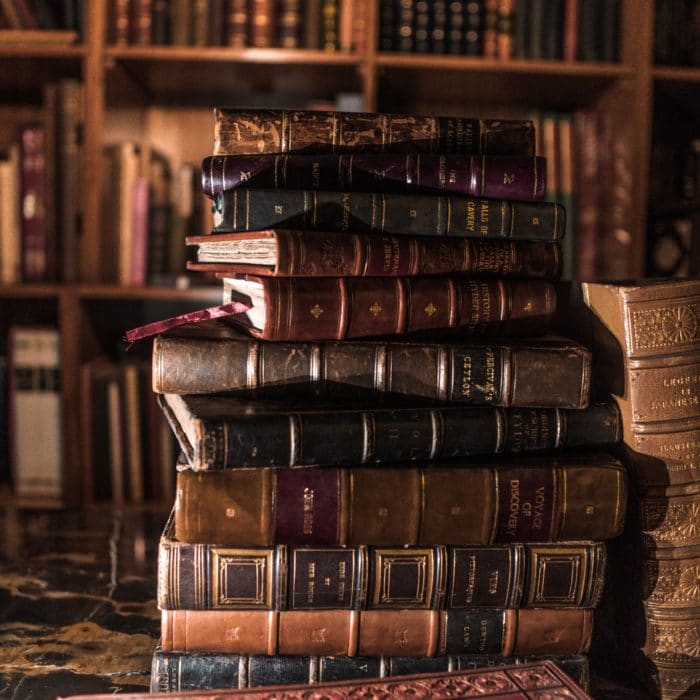 old books on table with bookshelves in background