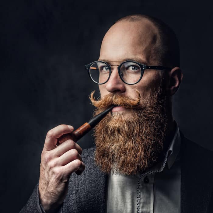 A man smoking pipe over grey background.