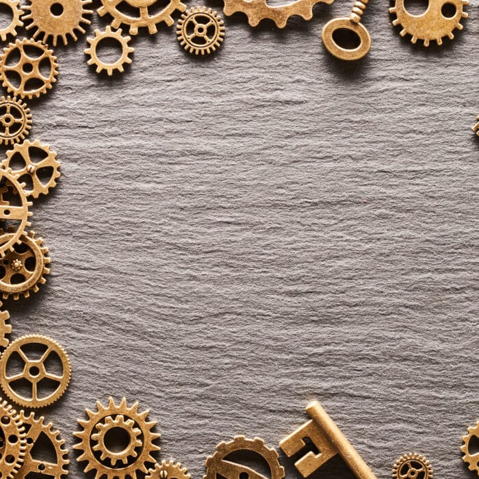 Various metal cogwheels, gear wheels and keys over slate background